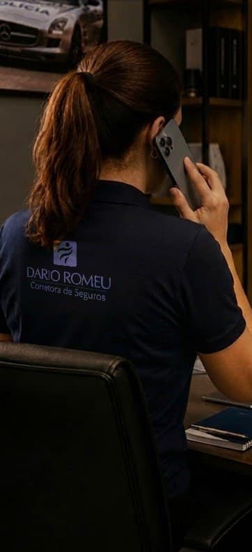 Atendente da corretora, de camisa Dario Romeu, ao telefone diante do notebook