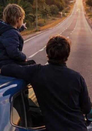 Pai e filho no carro, olhando a estrada ao pôr do sol