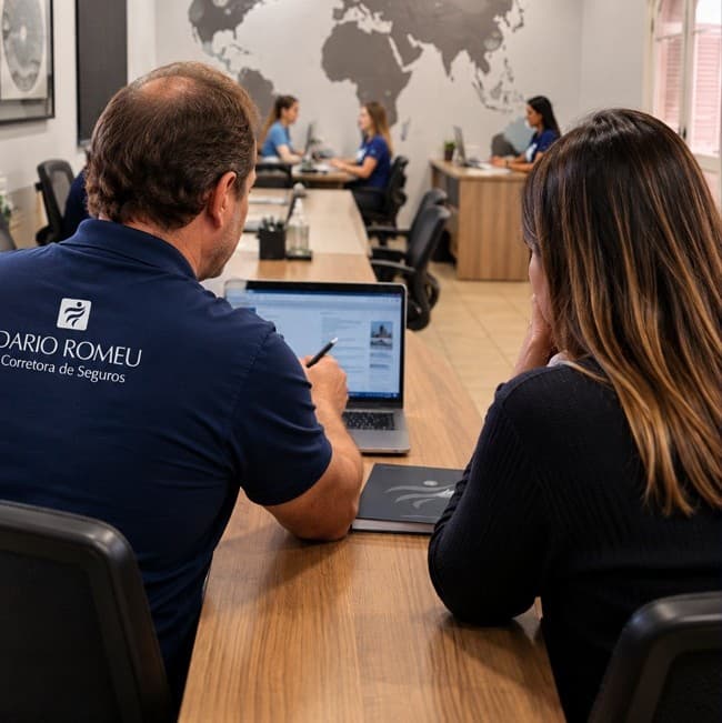 A equipe da Dario Romeu no escritório, de camisa da corretora, atendendo um cliente na mesa de reunião diante de um mapa-múndi