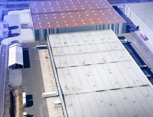 Vista aérea de galpões industriais com pátio de caminhões